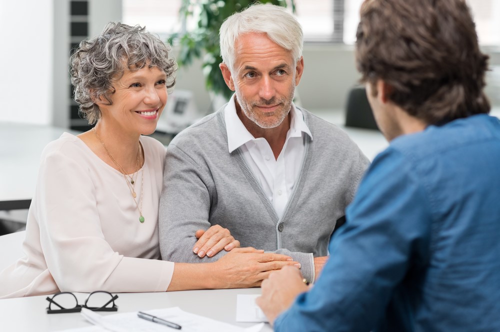 A husband and wife speaking with a long-term care insurance agent about their policy options