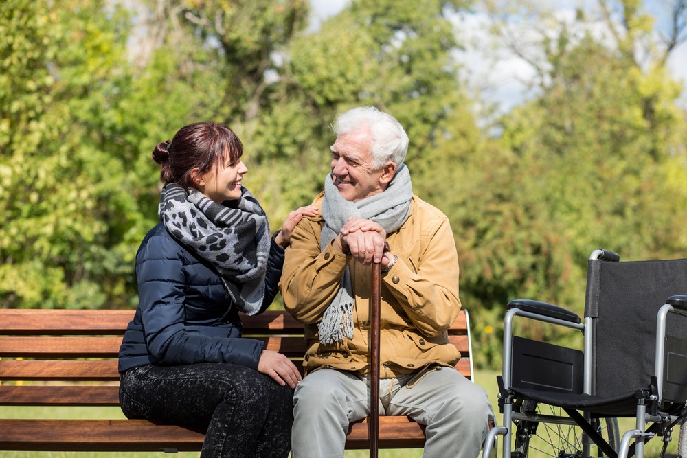 Elderly man sitting on a bench with his daughter. 