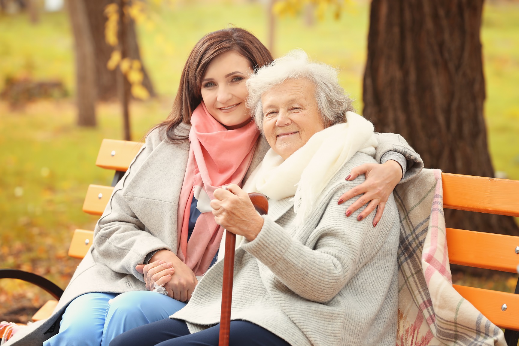 Daughter sitting with her elderly mother on a park bench. 